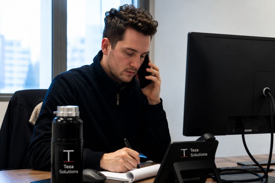 Mark Copilot team member on the phone, taking notes during a customer call